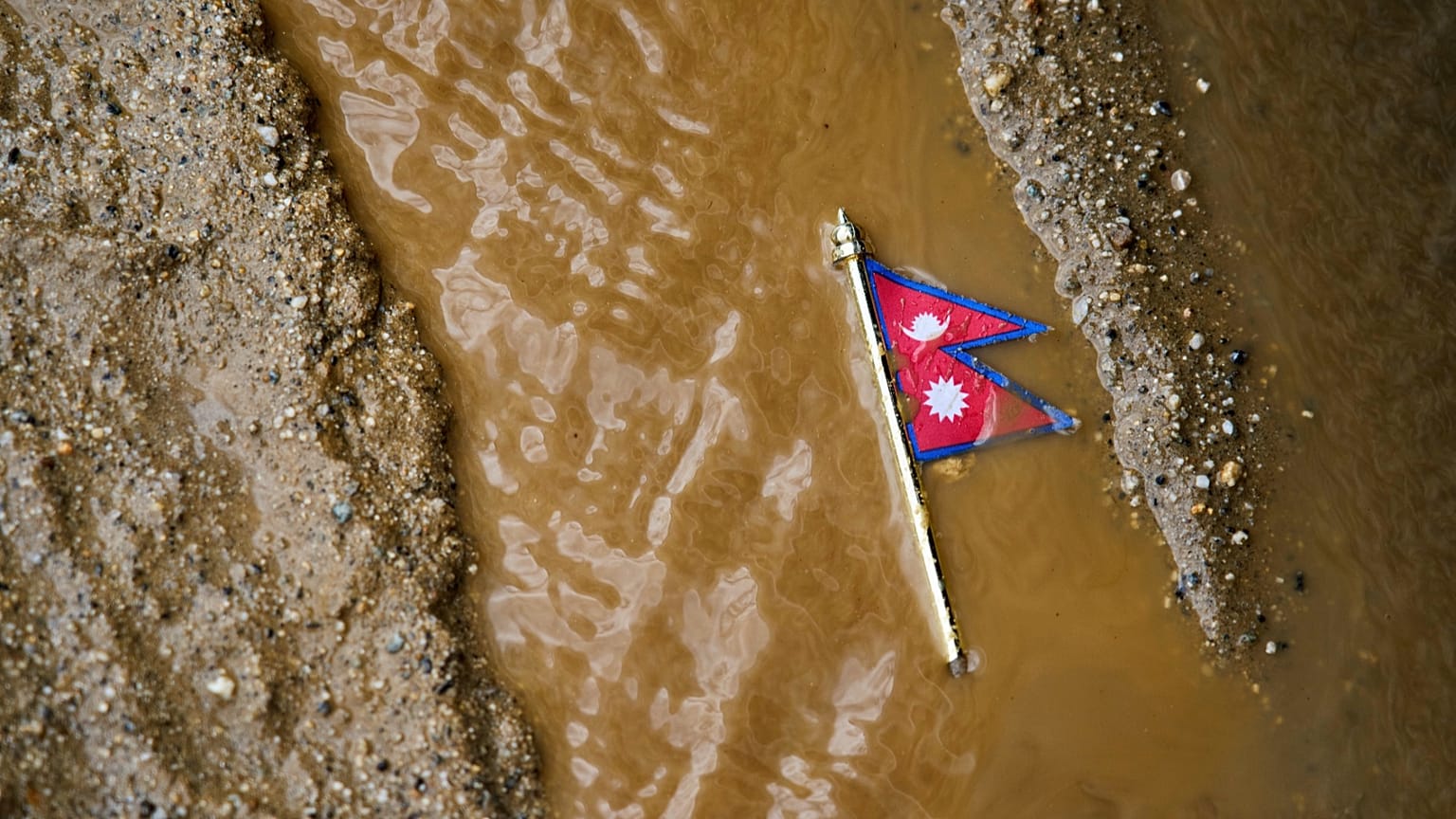 A Nepal flag lies on a muddy track near the banks of the Trishuli river in Dhading District, 30 August, 2026