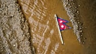 A Nepal flag lies on a muddy track near the banks of the Trishuli river in Dhading District, 30 August, 2026