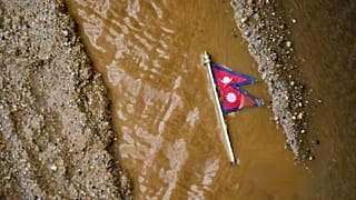 A Nepal flag lies on a muddy track near the banks of the Trishuli river in Dhading District, 30 August, 2026