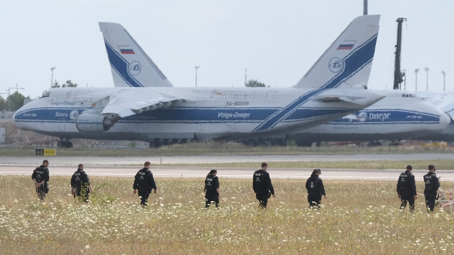 Police officers are walking across a field on the grounds of Leipzig Airport, Germany, Friday, Aug. 7, 2026, searching for a drone that may be connected to a suspected attack.
