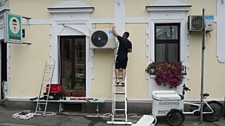 A worker installs a new air conditioning unit during a hot summer day in Belgrade, Serbia, June 30, 2026.