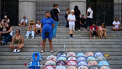Un vendeur ambulant vend des éventails près du Palais royal de Madrid, Espagne, le 20 août 2026.