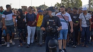 Inmigrantes que cruzaron de Marruecos a España son escoltados por la Policía Nacional tras ser desalojados de una playa en el enclave español de Ceuta el 20 de agosto de 2026.