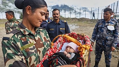 Żołnierz armii Nepalu patrzy na dwumiesięczne dziecko, uratowane razem z matką z rejonu dotkniętego nagłą powodzią w Dhunche w dystrykcie Rasuwa.