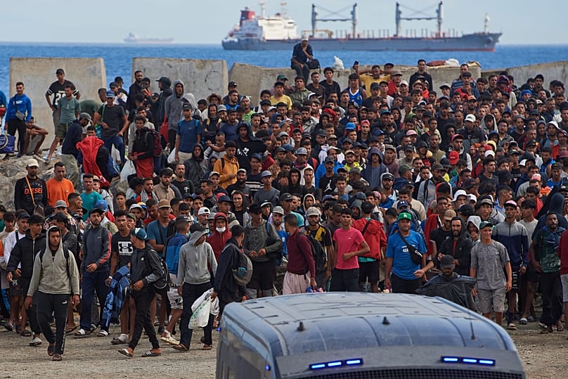 Migrants who crossed from Morocco into Spain return to a beach after being expelled from the area the previous day, as Spanish police escort them in the Spanish exclave.