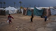 أطفال فلسطينيون نازحون يسيرون عبر مخيم خيام غارق بالمياه عقب هطول أمطار غزيرة في دير البلح، وسط قطاع غزة، الثلاثاء 24 فبراير/شباط 2026. (صورة من وكالة أسوشيتد برس/عبد الكريم ح