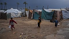 أطفال فلسطينيون نازحون يسيرون عبر مخيم خيام غارق بالمياه عقب هطول أمطار غزيرة في دير البلح، وسط قطاع غزة، الثلاثاء 24 فبراير/شباط 2026. (صورة من وكالة أسوشيتد برس/عبد الكريم ح