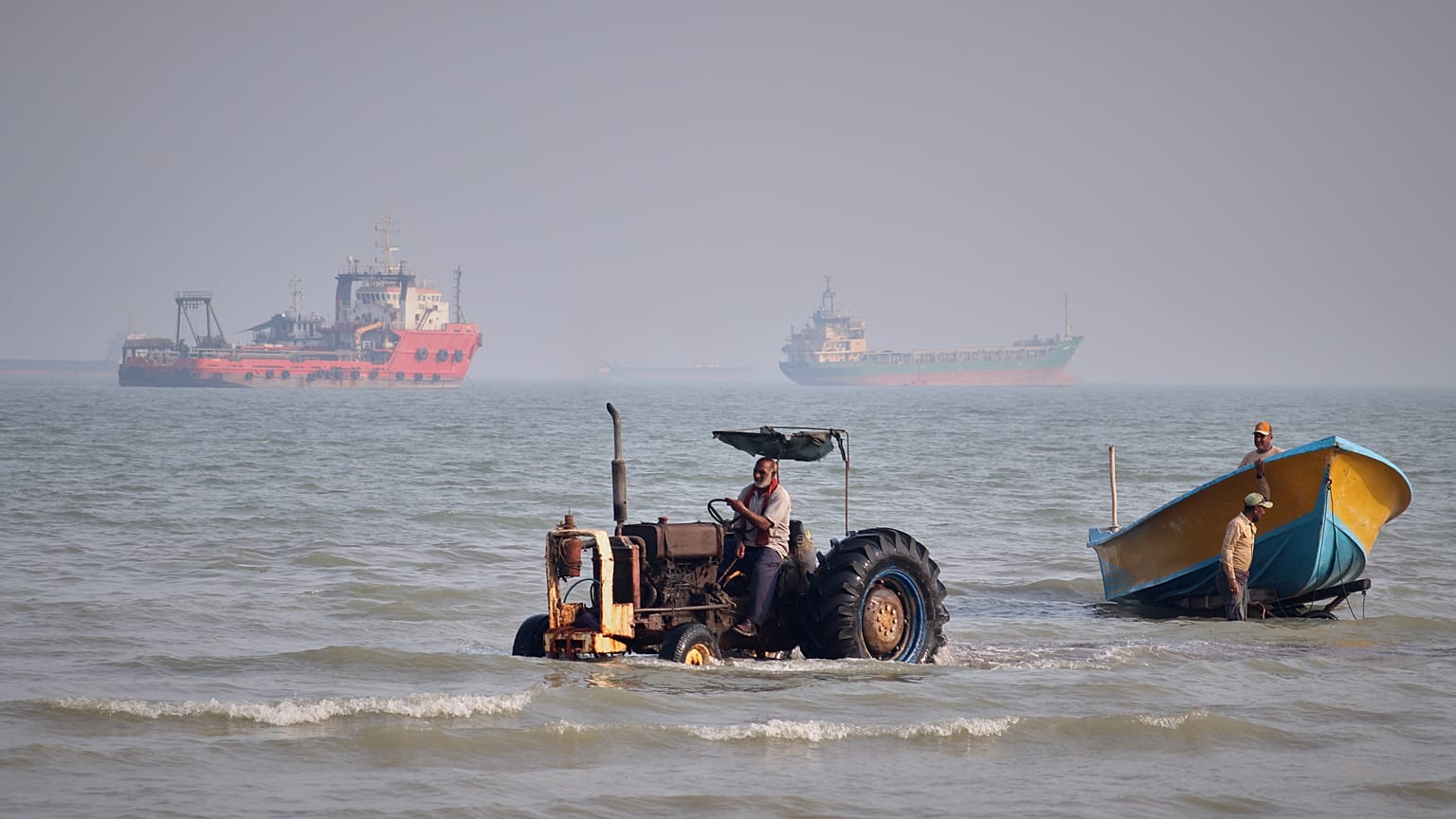 A tractor pulls a boat from the sea as commercial vessels are anchored in the Strait of Hormuz off Bandar Abbas, Iran, Monday, Aug. 31, 2026.