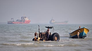 A tractor pulls a boat from the sea as commercial vessels are anchored in the Strait of Hormuz off Bandar Abbas, Iran, Monday, Aug. 31, 2026.