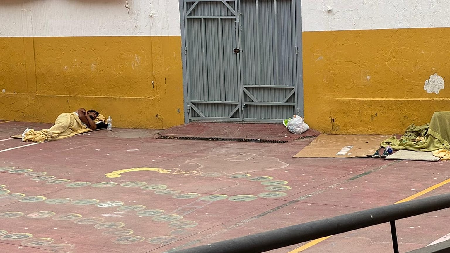 Un inmigrante duerme junto a una de las puertas de acceso del CEIP José Ortega y Gasset, en Ceuta, el 3 de septiembre de 2026.