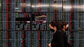 ARCHIVO - Varias personas pasan junto a un panel electrónico de cotizaciones en Taipei Exchange, en Taipéi, Taiwán, el lunes 30 de enero de 2023.