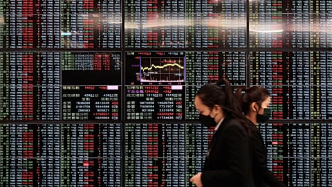 FILE - People walk past an electronic stock board at Taipei Exchange in Taipei, Taiwan, Monday, Jan. 30, 2023. 