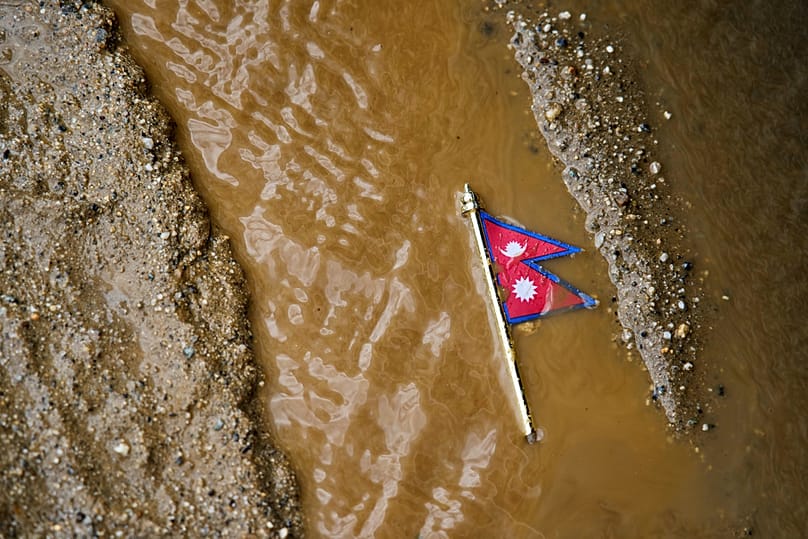 A Nepal flag lies on a muddy track near the banks of the Trishuli river in Dhading District, Nepal, Sunday, 30 August, 2026