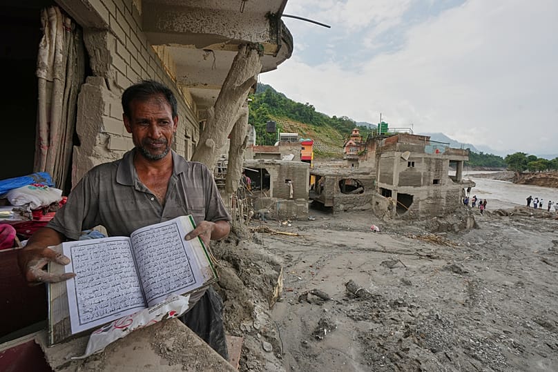 A resident shows a holy book as he salvages his belongings from damaged home filled with mud and debris in Devighat, in Nepal's Nuwakot district, Saturday, 29 August, 2026