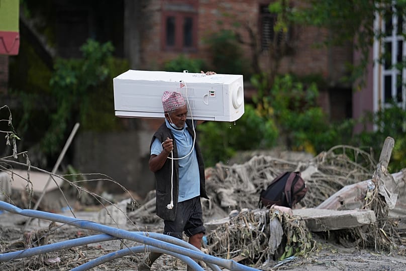 A resident carries an air cooler salvaged from his damaged house after flash flooding in the Devighat area of Nuwakot district, Nepal, Saturday, 29 August, 2026