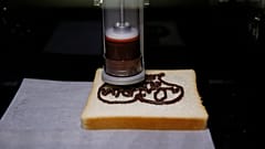 Εκτυπωτής τροφίμων 3D σχηματίζει σχέδιο από σοκολάτα σε φέτα ψωμιού (αρχείο).