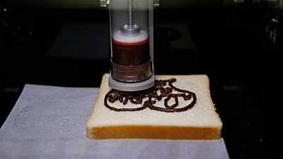 Εκτυπωτής τροφίμων 3D σχηματίζει σχέδιο από σοκολάτα σε φέτα ψωμιού (αρχείο).