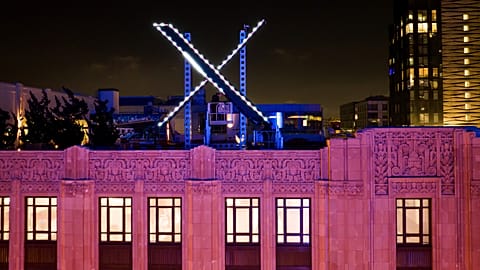 Workers install lighting on an "X" sign atop the company headquarters, formerly known as Twitter, in downtown San Francisco, on Friday, July 28, 2023. 