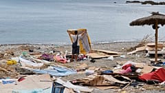 Un migrante que cruzó desde Marruecos a España recoge sus pertenencias tras ser desalojado de la playa del enclave español de Ceuta, el jueves 20 de agosto de 2026. 