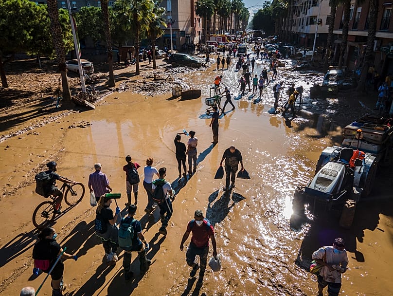 Des bénévoles et des habitants marchent dans la boue quatre jours après des crues soudaines à Paiporta, dans la banlieue de Valence, en Espagne, le samedi 2 novembre 2024
