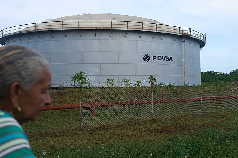 Venezuela'nın devlet petrol şirketi PDVSA'ya ait bir petrol depolama tankının yakınında yürüyen bir kadın, Cabimas, Venezuela, Salı, 1 Eylül 2026