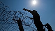 FILE - Hungarian soldiers put up razor wire on top of a fence on the border with Serbia, in Asotthalom, Hungary, on 31 August 2015.