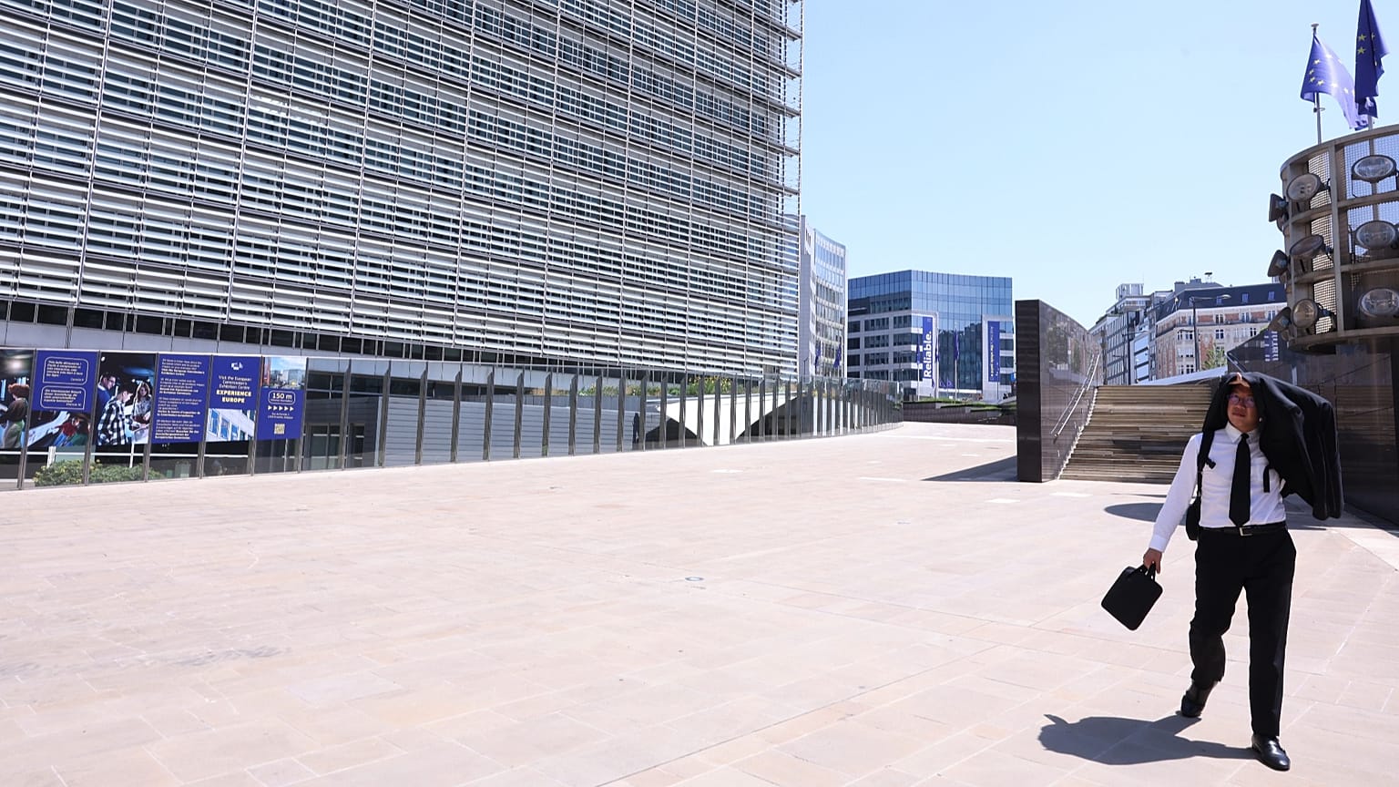A man uses his suit jacket to shelter from the sun as he walks in the EU quarter of Brussels, 25 June, 2026