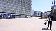 A man uses his suit jacket to shelter from the sun as he walks in the EU quarter of Brussels, 25 June, 2026