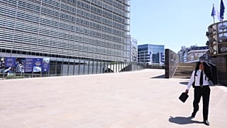 A man uses his suit jacket to shelter from the sun as he walks in the EU quarter of Brussels, 25 June, 2026