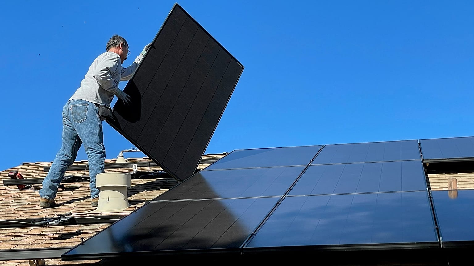 Ein Mann montiert Solarmodule auf einem Dach.