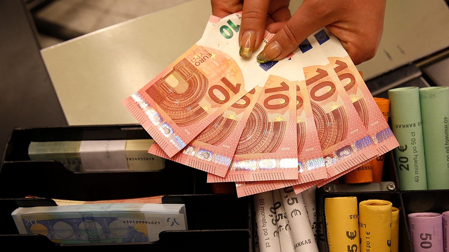 A Thursday, Jan. 1, 2015 photo from files showing euro coins and banknotes shown by a salesclerk at a shop in Vilnius, Lithuania