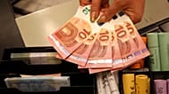 A Thursday, Jan. 1, 2015 photo from files showing euro coins and banknotes shown by a salesclerk at a shop in Vilnius, Lithuania