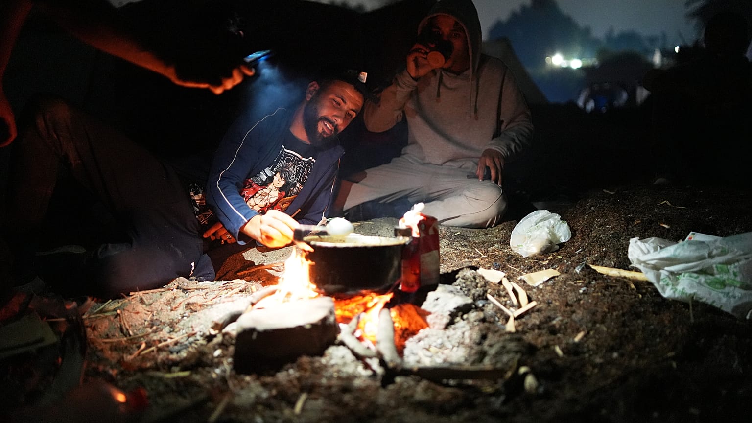 Un par de inmigrantes en la playa de El Trampolín mientras cocinan 