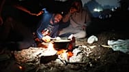 Un par de inmigrantes en la playa de El Trampolín mientras cocinan 