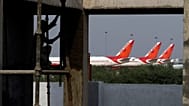 Air India planes are parked in a row, as a laborer works at a construction site outside the Indira Gandhi International airport in New Delhi, India, Tuesday, May 8, 2012.