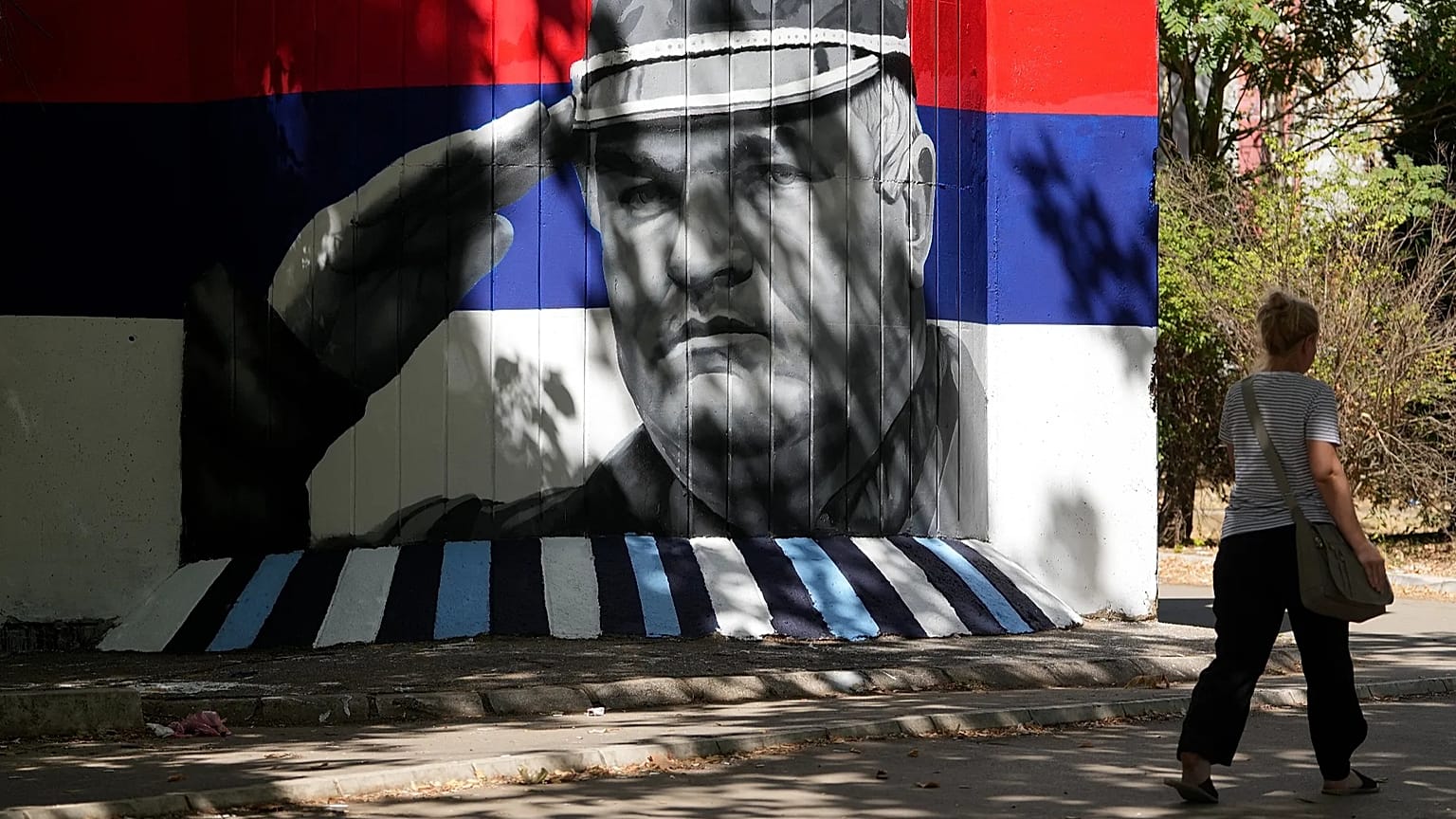 A woman walks by a mural that shows former Bosnian Serb wartime general Ratko Mladic in Belgrade, Serbia, Wednesday, Sept. 2, 2026. 