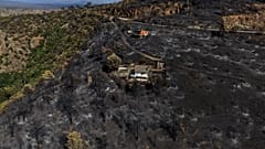 An area scorched by a wildfire surrounds structures in El Tiemblo, Avila province, Spain, Thursday, July 30, 2026.