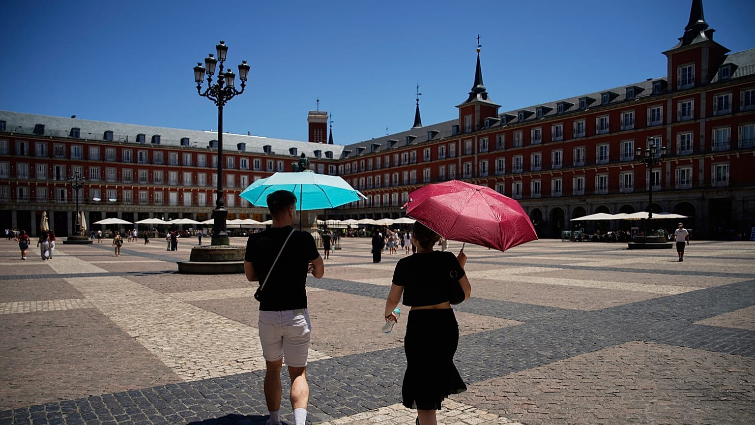 Turistas levam guarda-chuvas para se protegerem do sol enquanto passeiam pelo centro de Madrid, Espanha, quinta-feira, 2 de julho de 2026. (AP Photo/Andrea Comas)