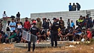 Migrantes que cruzaron de Marruecos a España regresan a una playa, mientras la Policía Nacional los escolta en el enclave español de Ceuta, el 21 de agosto de 2026.
