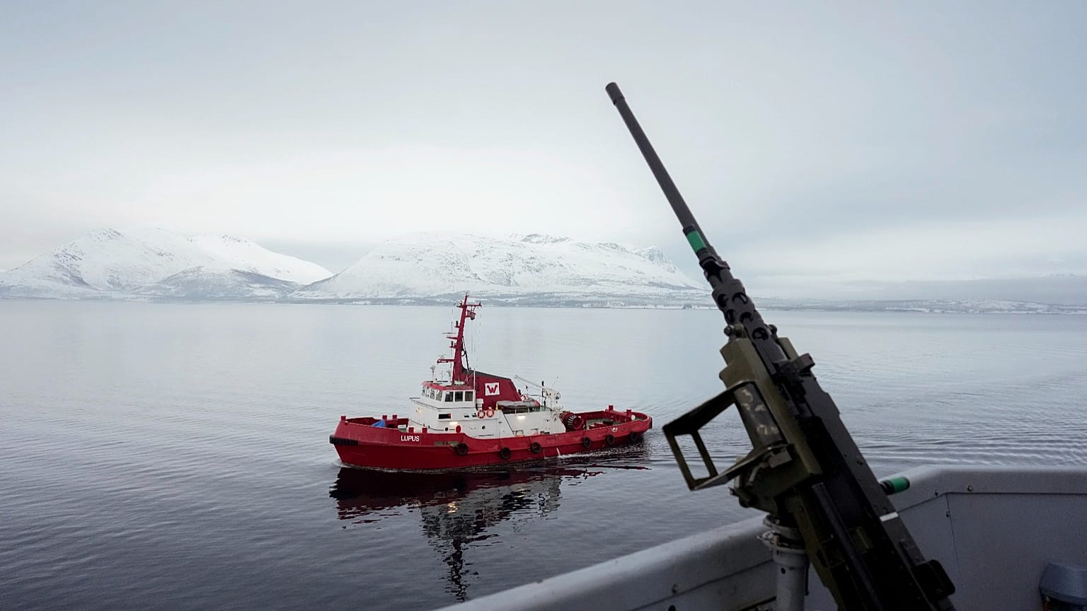 A tugboat sails alongside the French navy frigate Normandie before it docks during a patrol in a Norwegian fjord, north of the Arctic circle, Friday 8 March 2024. 