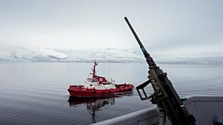 A tugboat sails alongside the French navy frigate Normandie before it docks during a patrol in a Norwegian fjord, north of the Arctic circle, Friday 8 March 2024. 