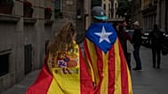 Una niña envuelta en una bandera española y un niño envuelto en una bandera catalana caminan juntos por el centro de Barcelona, ​​España, en noviembre de 2017.
