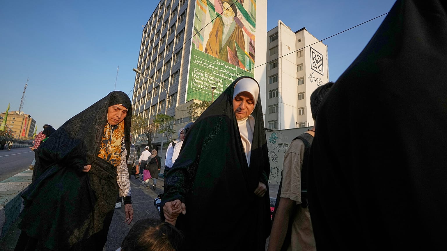 نساء يمررن بلوحة إعلانية تصور الزعيم الثوري الإيراني الراحل آية الله روح الله الخميني أثناء توجههن إلى احتفال في الشارع بمناسبة عيد ميلاد النبي محمد في طهران، إيران
