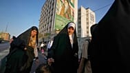 نساء يمررن بلوحة إعلانية تصور الزعيم الثوري الإيراني الراحل آية الله روح الله الخميني أثناء توجههن إلى احتفال في الشارع بمناسبة عيد ميلاد النبي محمد في طهران، إيران