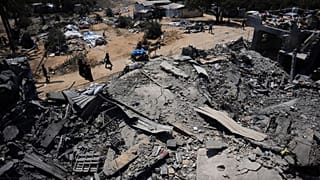 فلسطينيون يسيرون بجوار مستودع للمساعدات الغذائية تضرر جراء غارة جوية إسرائيلية استهدفت منزلاً مجاوراً في دير البلح بوسط قطاع غزة، يوم الأربعاء، 26 أغسطس 2026.