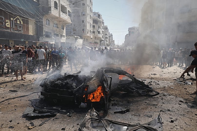 Palestinians gather around the burning wreckage of a car after an Israeli army strike in Gaza City, 31 August, 2026