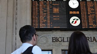A couple stands in front of a billboard displaying canceled trains during a nationwide general strike called by the labor unions, in Milan, Italy, Friday, May 29, 2026. (AP Ph