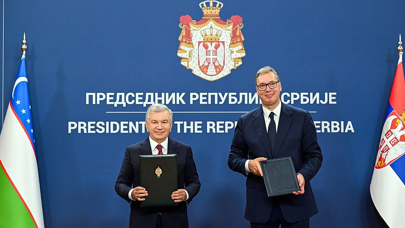 Usbekistans Präsident Schawkat Mirsijojew und Serbiens Präsident Aleksandar Vučić halten unterzeichnete Dokumente in die Kamera.
