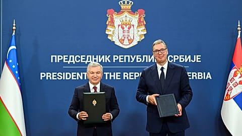 Uzbek President Shavkat Mirziyoyev and Serbian President Aleksandar Vučić hold signed documents.