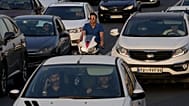 مردی در ترافیک عصرگاهی شمال تهران، ایران، سه‌شنبه، ۲ ژوئیه ۲۰۲۴، با موتورسیکلت خود در میان ماشین‌ها می‌راند